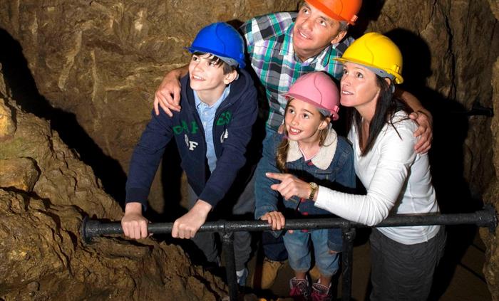 A family looking over a rail at someone just out of shot, all are wearing hard hats.